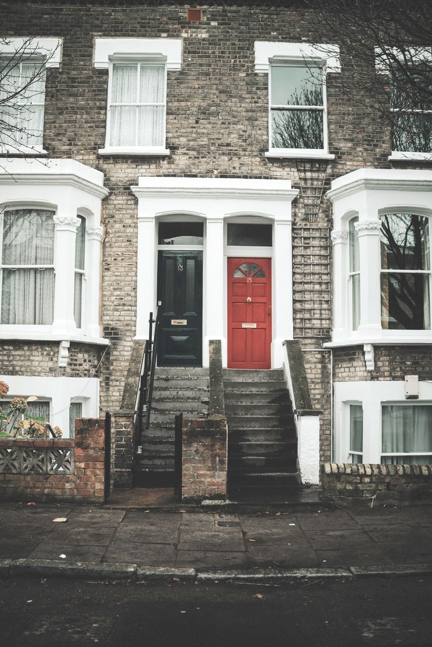 A row of London terraced houses with red and black front doors